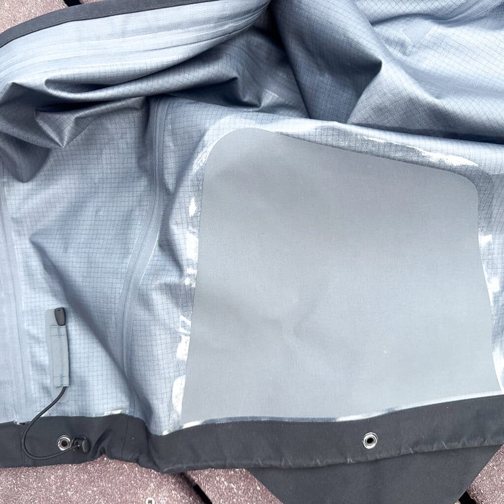 A photo of the cuff wide open. Note the cinch cord on the left, the absence of a snow gaiter, and the laminated cuff guard. 